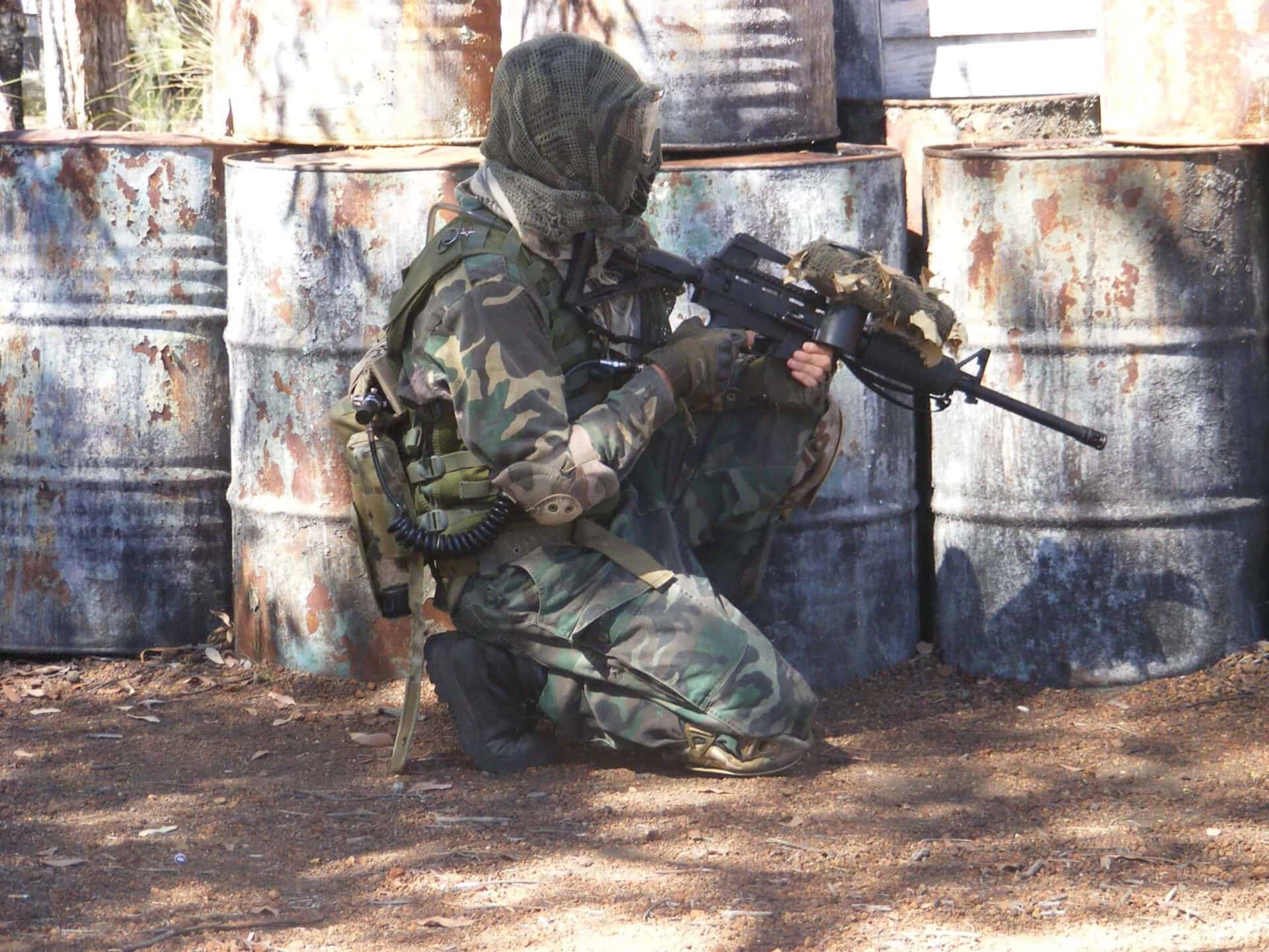 Paintball player hiding behind barrels