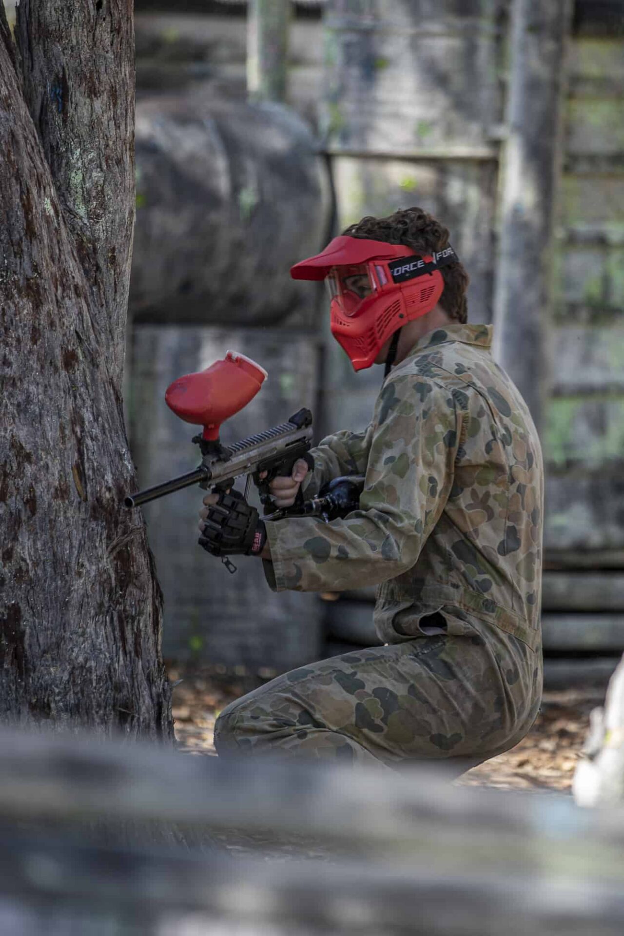 Paintball player hiding behind a tree