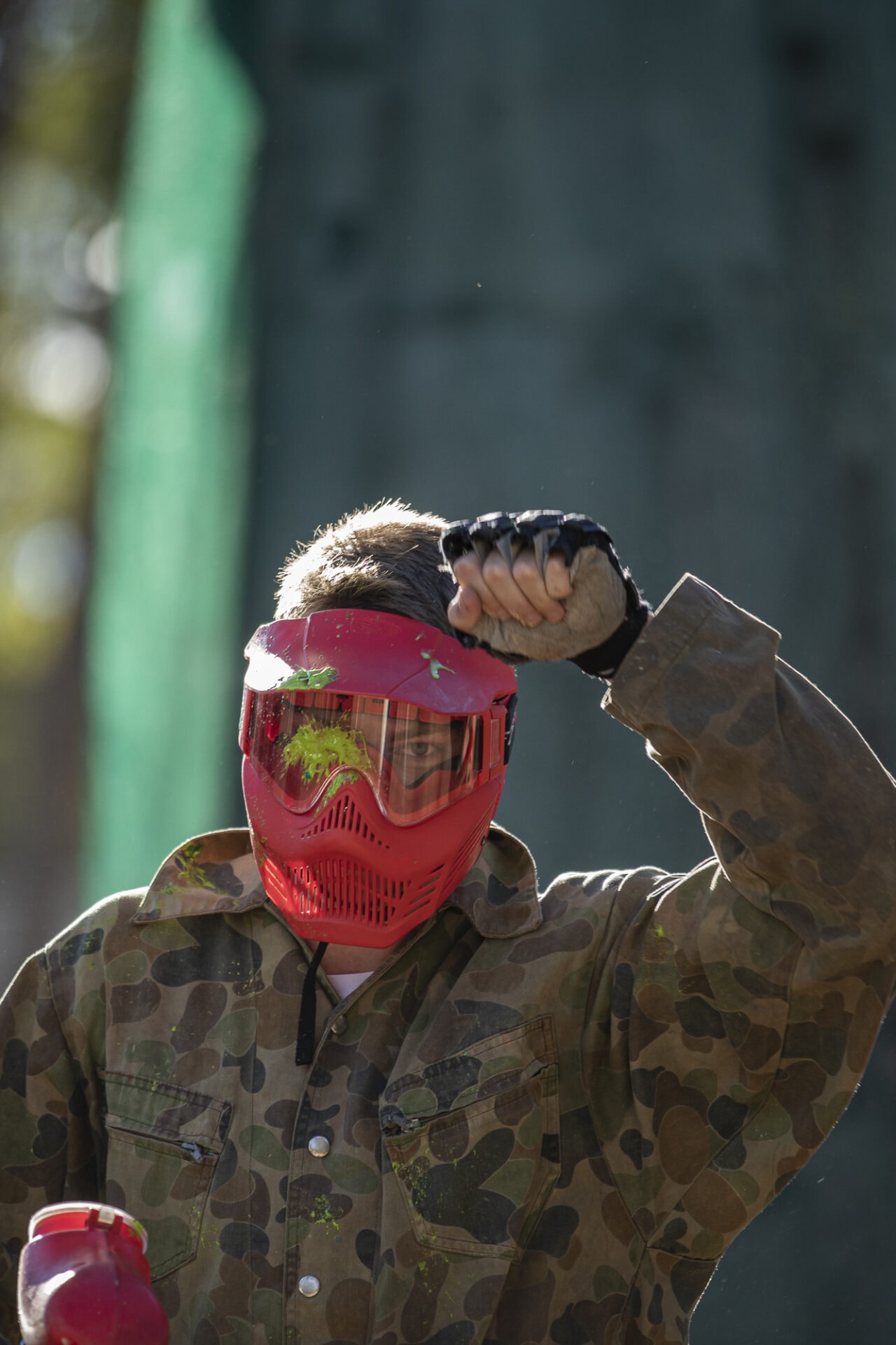 Paintball player holding his hand up after headshot
