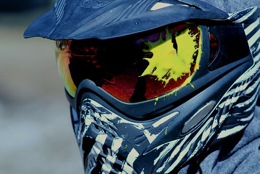 A helmet that has been shot in the eye with a paintball splat