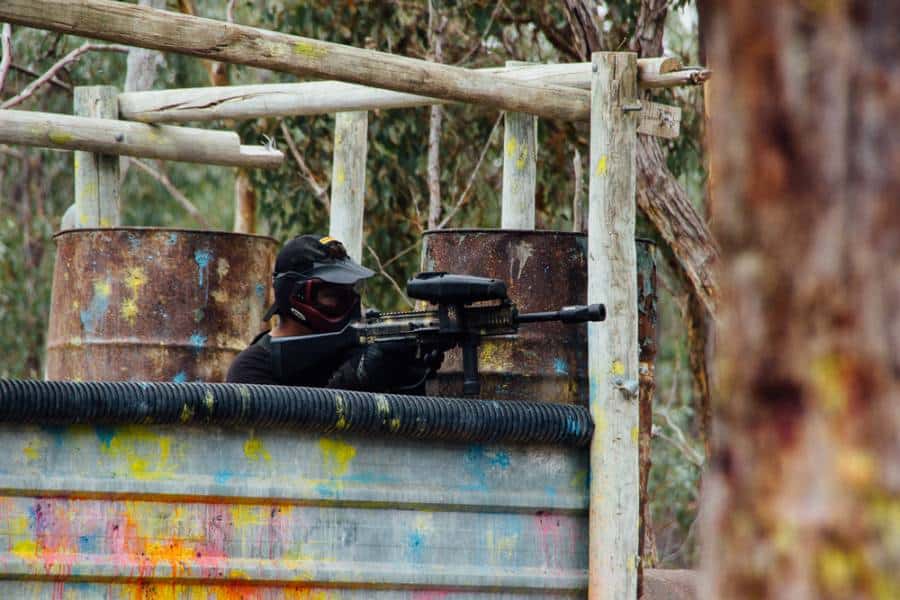 Paintball player taking aim from behind barricade